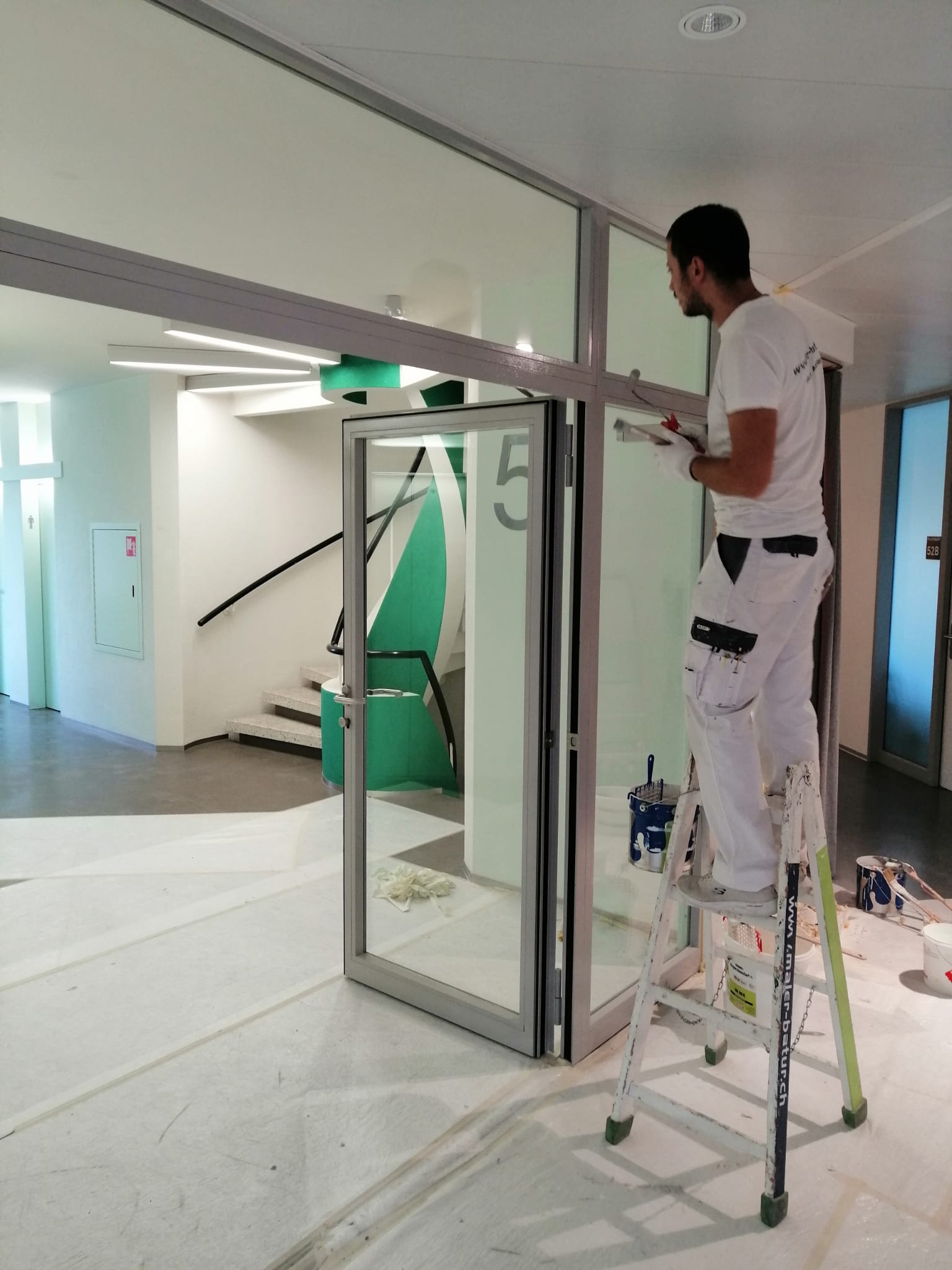 Maler beim Streichen eines Rahmens im Treppenhaus.